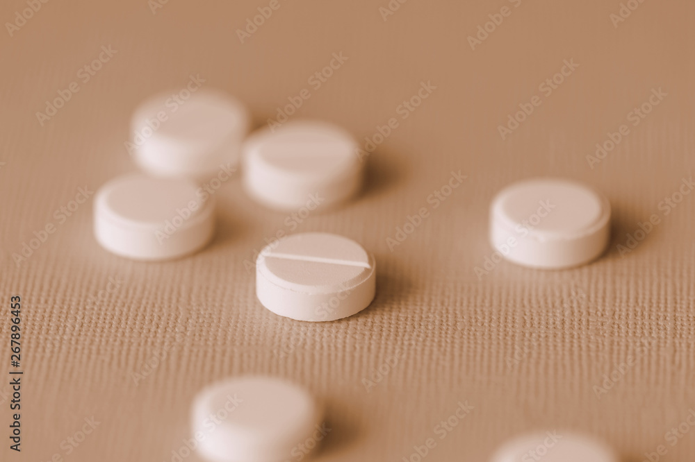 White tablets scattered on a surface close up. Brown color toned White tablets scattered on a surface close up. Brown color toned