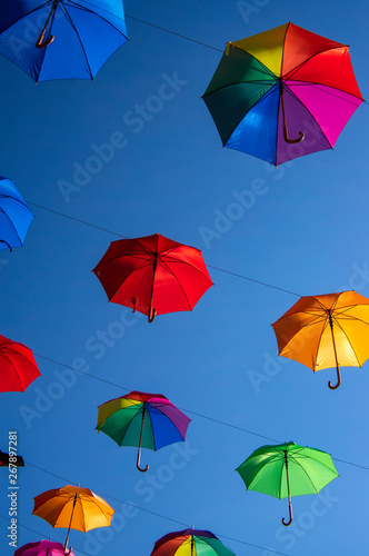Group of umbrellas hanging on a rope isolated against blue background  wallpaper background  bright various colors scenery