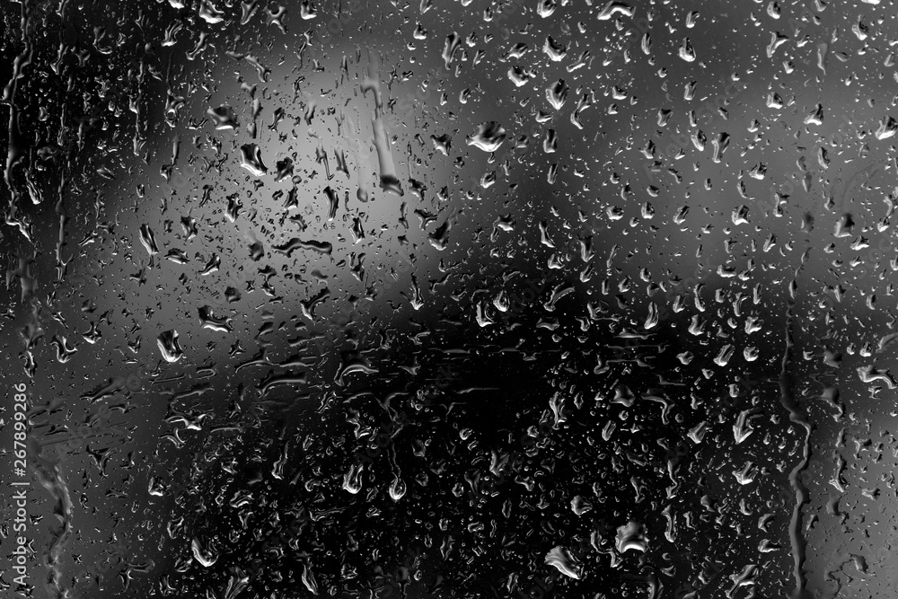 Obraz premium Raindrops on glass in rainy weather close up. Natural background black and white