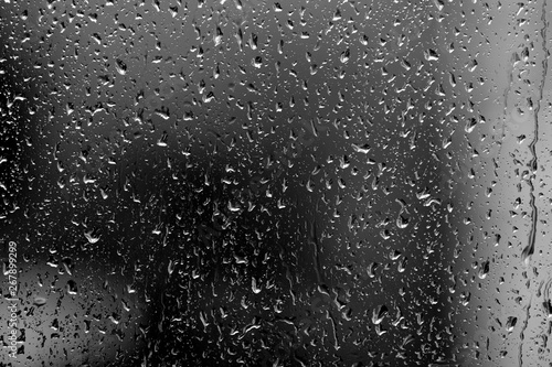 Raindrops on glass in rainy weather close up. Natural background black and white