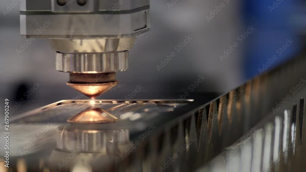 Cutting of metal. Sparks fly from laser. Industrial laser cutter with sparks. The programmed robot head cuts with the aid of a huge sheet of metal temperature Cutting of metal. Sparks fly from laser. Industrial laser cutter with sparks. The programmed robot head cuts with the aid of a huge sheet of metal temperature