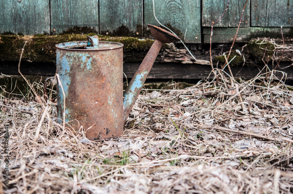 old watering can on wooden background old watering can on wooden background