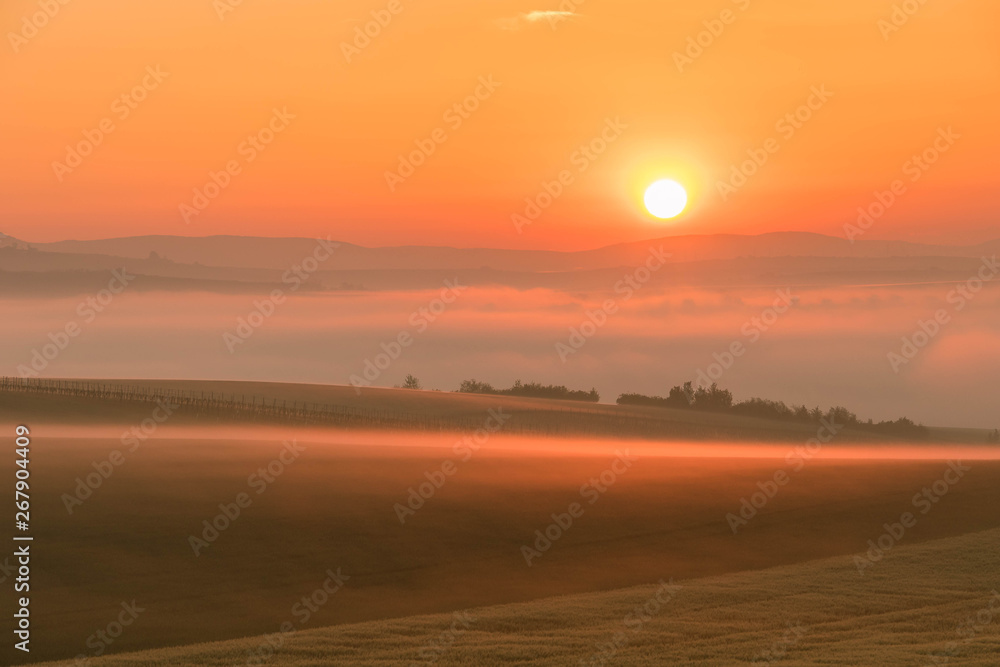 Fototapeta premium Landscape of the colorful sunrise over the foggy hills and fields
