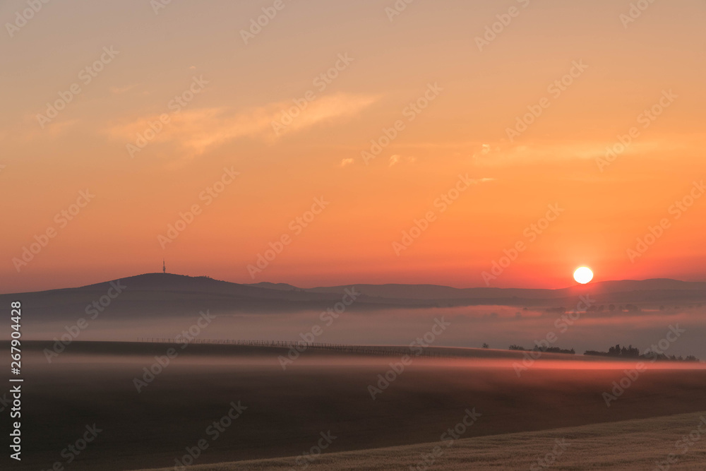 Landscape of the colorful sunrise over the foggy hills and fields