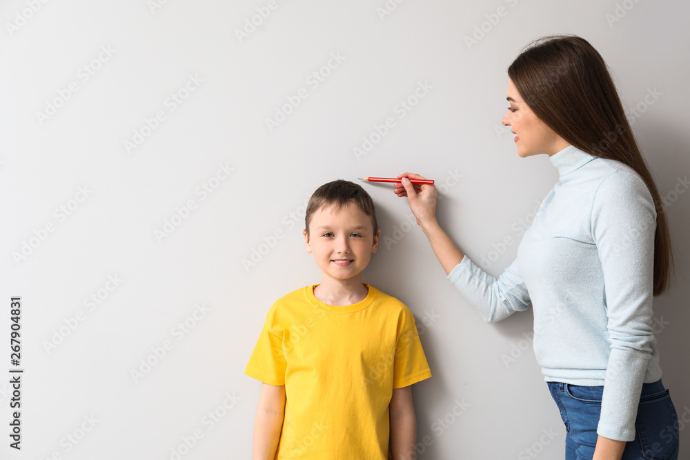 Mother measuring height of her son near wall Mother measuring height of her son near wall