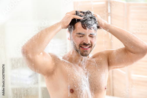 Handsome man washing hair a...