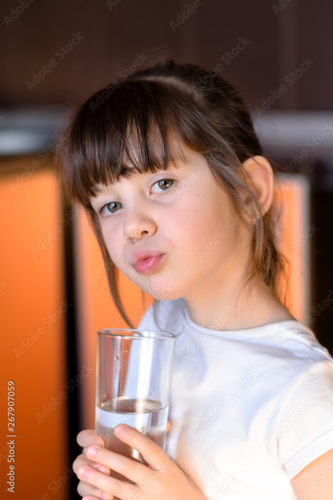 Adorable little girl drinking water in kitchen and sending kiss. Health and beauty concept Adorable little girl drinking water in kitchen and sending kiss. Health and beauty concept