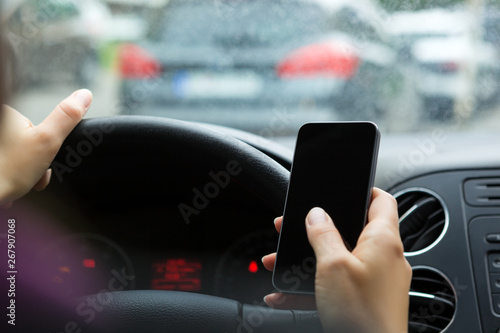 Woman sitting in the car and messaging on mobile phone.