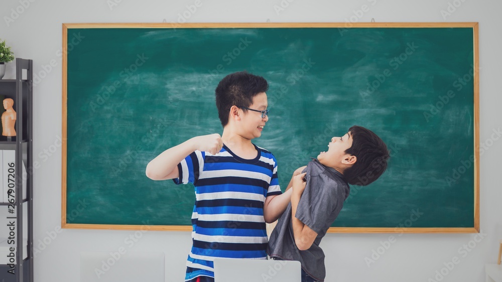 Asian school boy quarreling punching bullying weak friend on