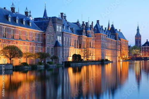 Reflections of the Binnenhof (13 century gothic castle) on the Hofvijver lake at dusk during the blue hour, with the clock tower of Grote of Sint Jacobskerk on the right, The Hague, Netherlands photo