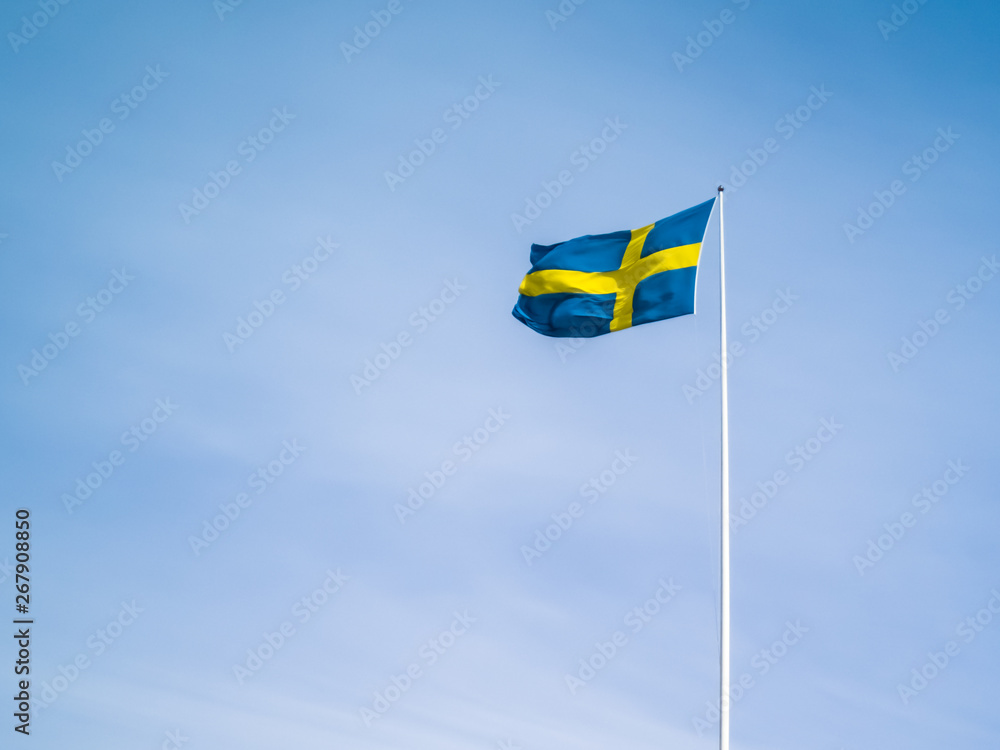 Swedish flag against blue sky. Swedish flag fluttering on wind. Sveriges nationaldag. National Day of Sweden. Swedish Flag Day. Swedish flag against blue sky. Swedish flag fluttering on wind. Sveriges nationaldag. National Day of Sweden. Swedish Flag Day.