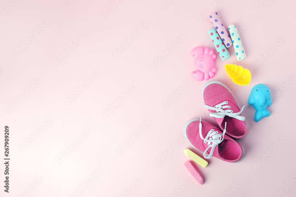 Toys and pink sneakers on pastel background from above with copy space. Childhood - holiday or summer fun concept.