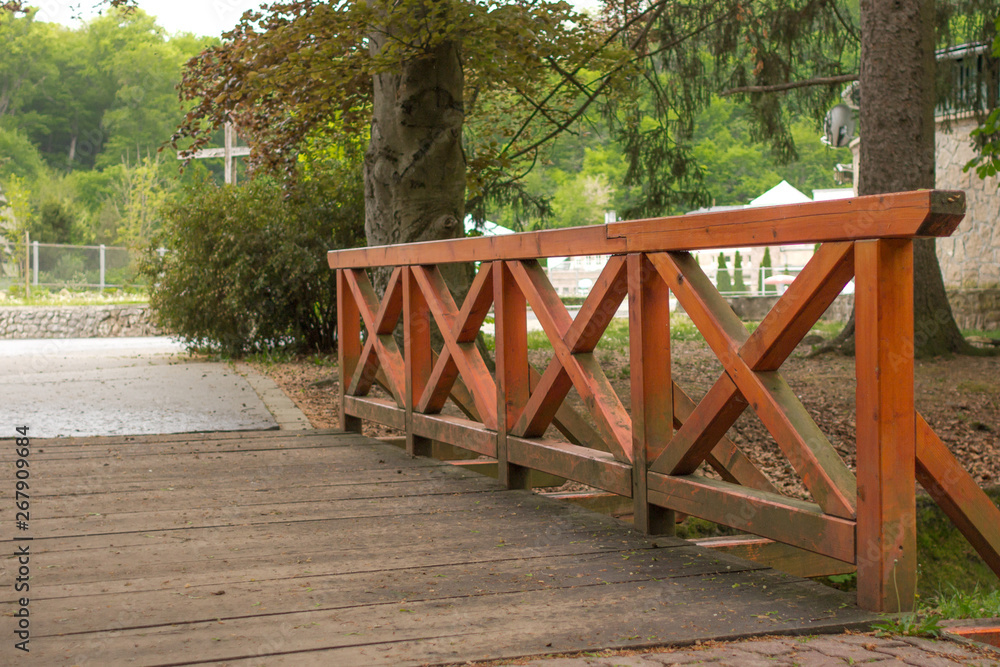 Wooden bridge Stream in the park. Perspective in architecture. Bridge with orange railing over the river. Rain in an empty park. Wet asphalt. Wooden bridge Stream in the park. Perspective in architecture. Bridge with orange railing over the river. Rain in an empty park. Wet asphalt.