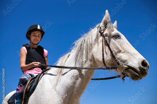 10 years old girl is riding a white horse