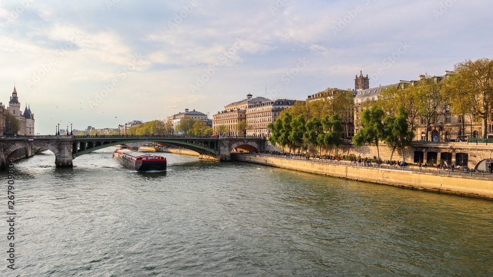 Beautiful cityscape of Paris, bridge Pont Sully across Seine river and a ship. France. April 2019