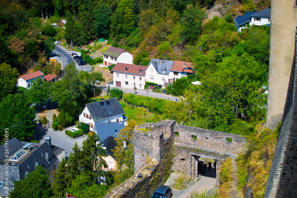 View of the wall of Vianden Castle and houses in the forest and mountain in Vianden, Luxembourg