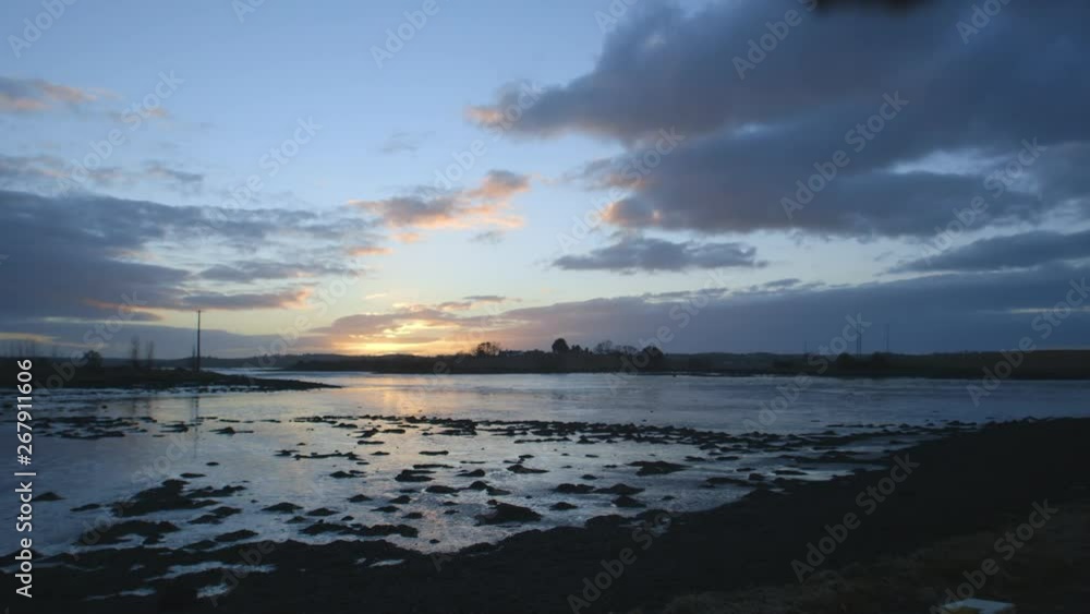 Steady, exterior, wide shot of a desolate, frozen lake and a setting sun. Steady, exterior, wide shot of a desolate, frozen lake and a setting sun.