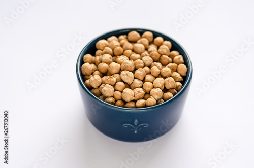 Blue bowl with dried chickpeas on white background