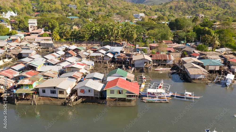 Naklejka premium Aerial view Coron city with slums and poor district. Palawan.Wooden houses near the water.Poor neighborhoods and slums in the city of Coron aerial view