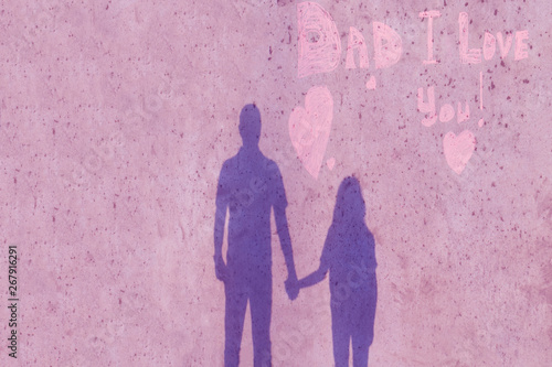 Happy dad holds daughter's hand. Shadow of dad and daughter on the wall. On the wall the inscription Dad I love you. Concept of happy father day.