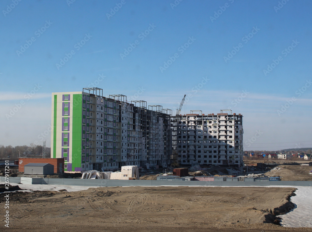 construction of a large multi-storey building in a new residential quarter in the city near the old wooden houses in Novosibirsk