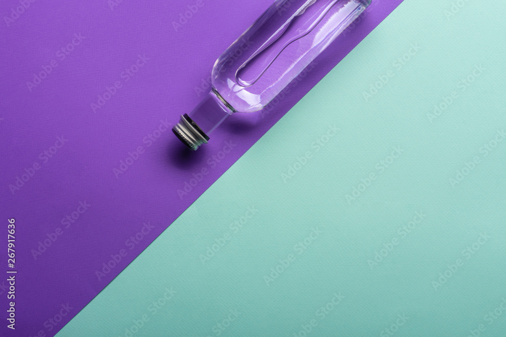 transparent wineglass and bottle with water on bright purple and azure background transparent wineglass and bottle with water on bright purple and azure background