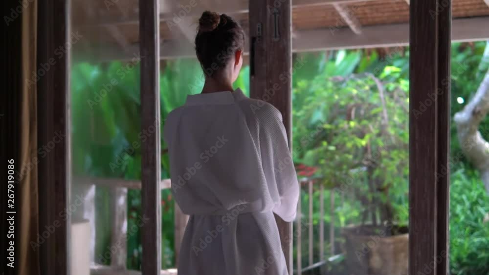 young woman in bathrobe comes out through French window outside, exotic lux room young woman in bathrobe comes out through French window outside, exotic lux room