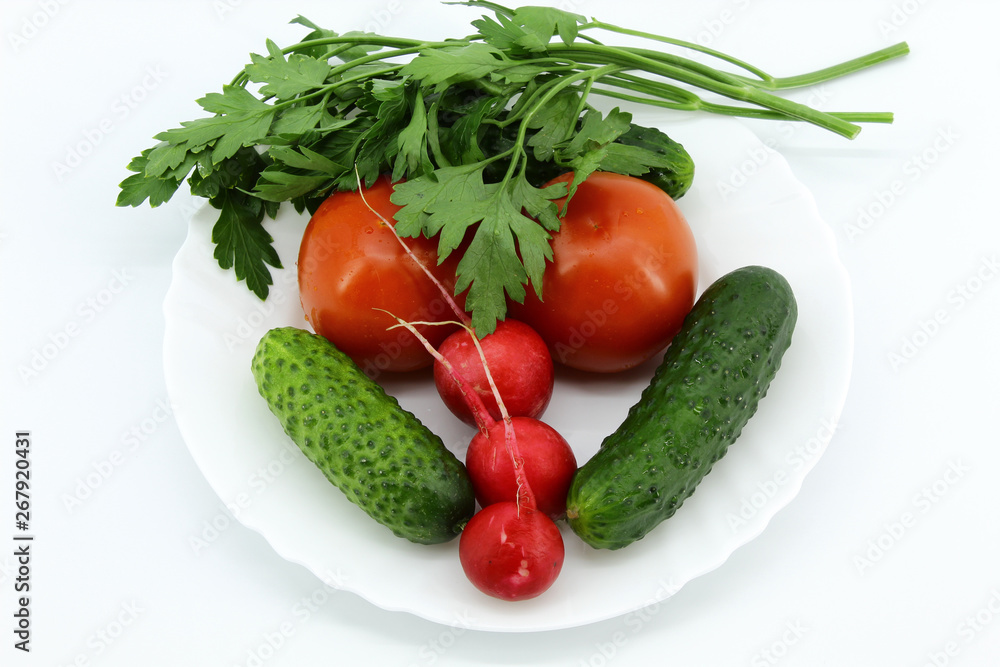 Two tomatoes, two cucumbers, three radishes, a bunch of parsley on a plate. White background Two tomatoes, two cucumbers, three radishes, a bunch of parsley on a plate. White background