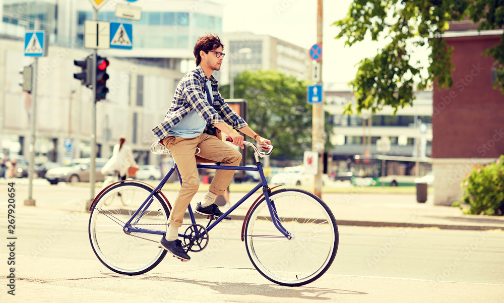 Fototapeta premium people, style, leisure and lifestyle - young hipster man with shoulder bag riding fixed gear bike on city street