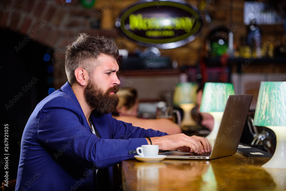 Manager work online while enjoy coffee. Online job. Hipster freelancer work online blog notebook. Surfing internet. Freelance benefit. Man bearded businessman sit pub with laptop and cup of coffee Manager work online while enjoy coffee. Online job. Hipster freelancer work online blog notebook. Surfing internet. Freelance benefit. Man bearded businessman sit pub with laptop and cup of coffee