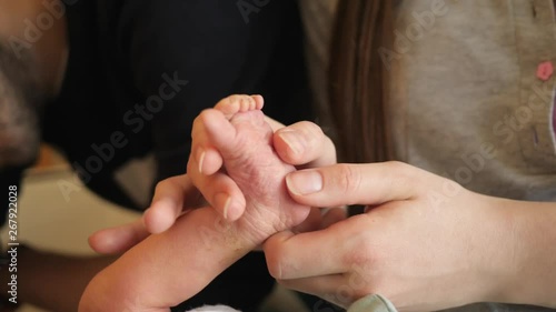 Tender mother fingers making massage to newborn baby small foot care in maternity hospital couple of days after birth photo