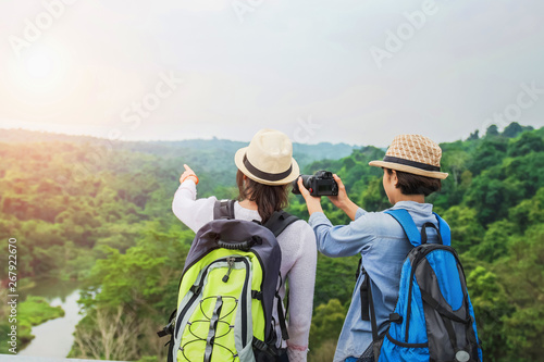 Two Asian tourists are taking pictures of the forest on the mountain. Travel in the holiday concept