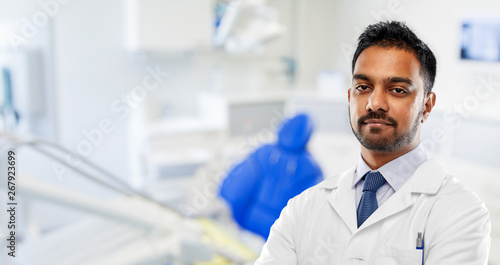 medicine  dentistry and healthcare concept - indian male dentist in white coat over dental clinic office background
