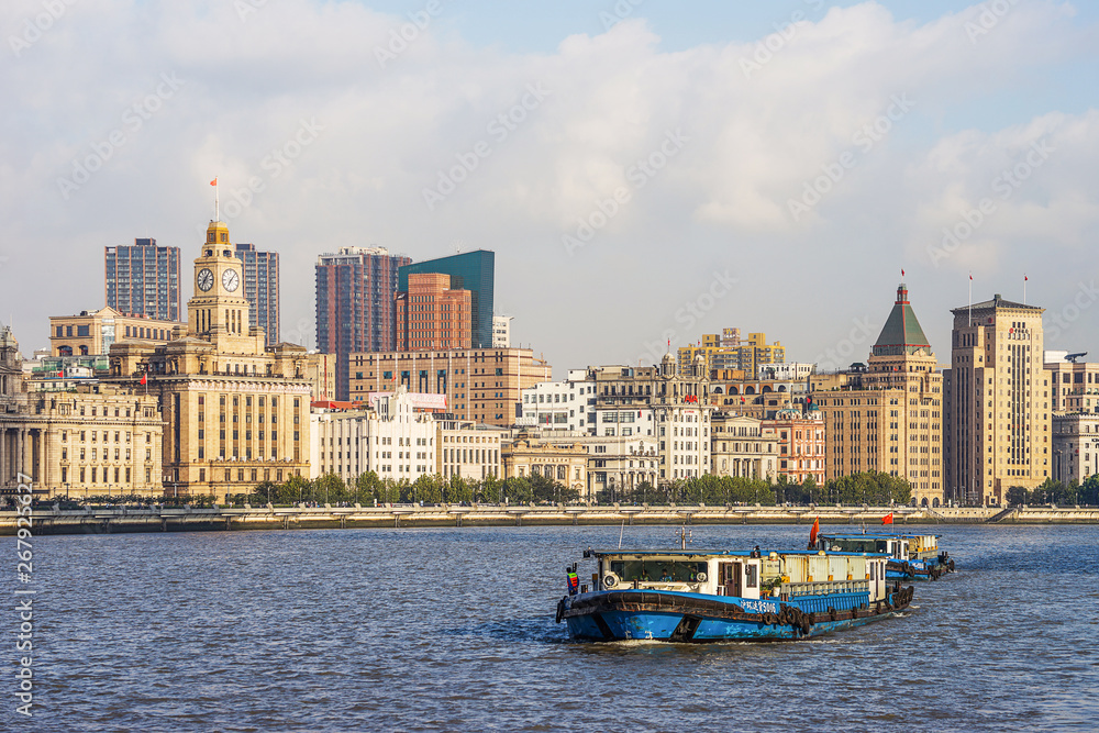 Obraz premium A household waste container ship is traveling on the Huangpu River on the Bund, a historic scenic spot in Shanghai