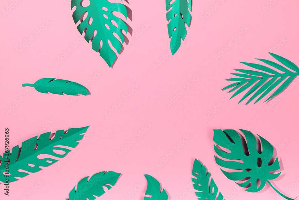 Fototapeta premium tropical leaves cut from paper on a pink background.