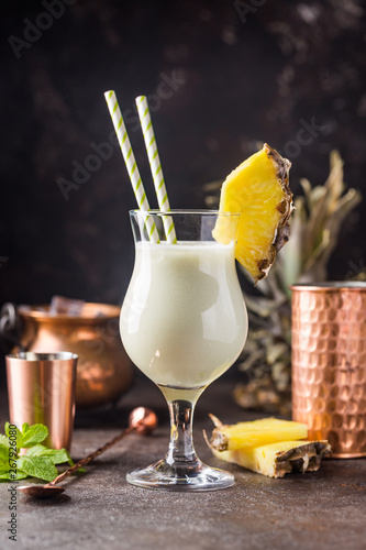 Homemade frozen Pina Colada cocktail with rum, coconut milk and pineapple garnish over black background