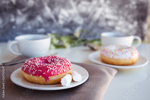 Glazed donut with black coffee and marshmallows. Pink and white tasty donuts on a table. Morning breakfast.