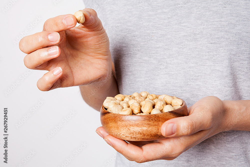 Obraz premium Woman's in hand hazelnut in a bowls. Healthy food and snack.