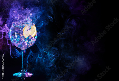 gin tonic cocktail splashing in blue and purple smoky background. photo