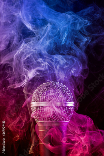 microphone enveloped in a colored cloud of smoke on black background.