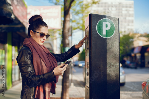 beautiful young woman pays for Parking in meter on the street