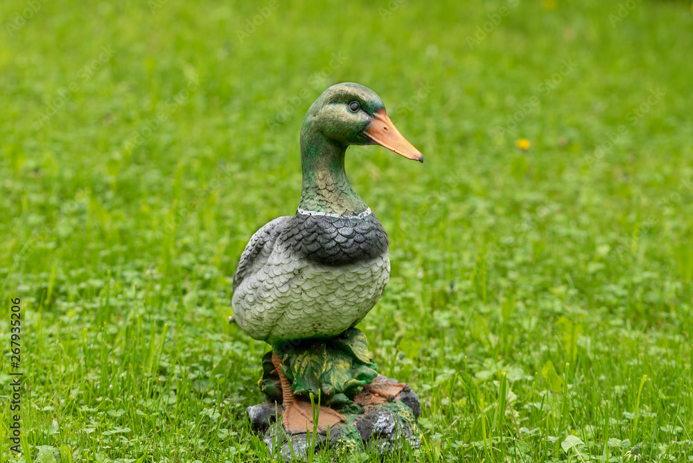 Close-up of a decorative figure of a duck on a background of green grass. Close-up of a decorative figure of a duck on a background of green grass.