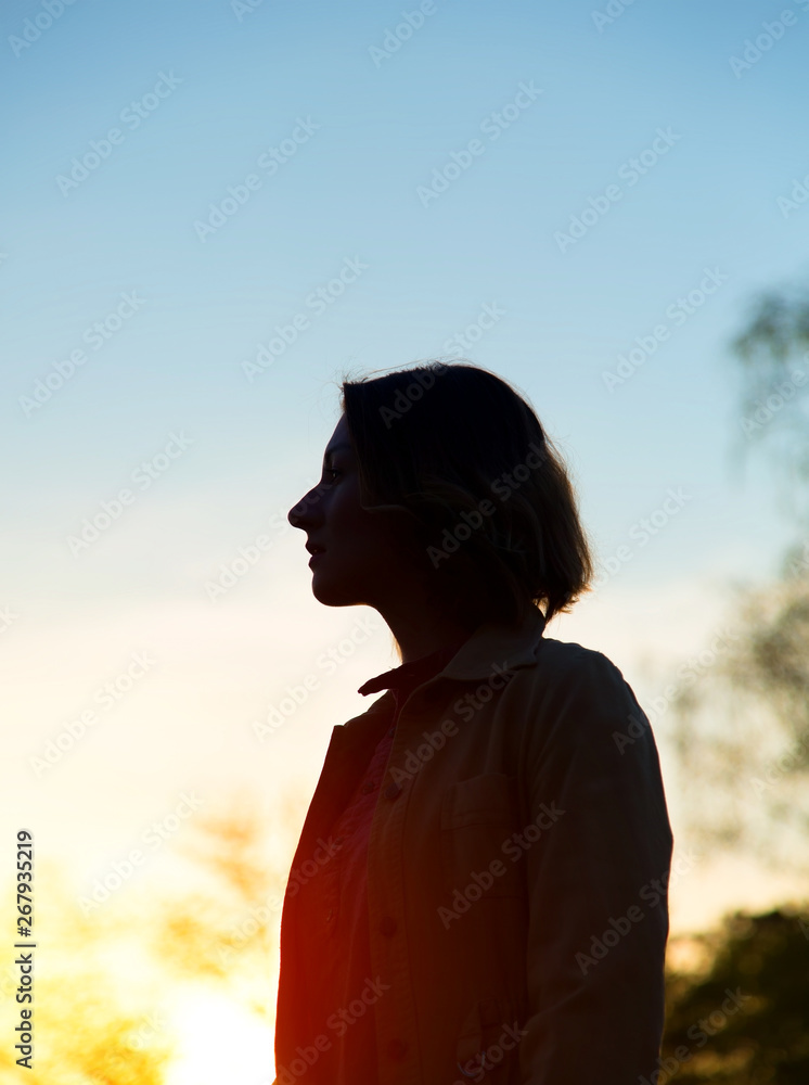 Silhouette of a woman against the backdrop of the sunset, the forest and the blue sky. Silhouette of a woman against the backdrop of the sunset, the forest and the blue sky.