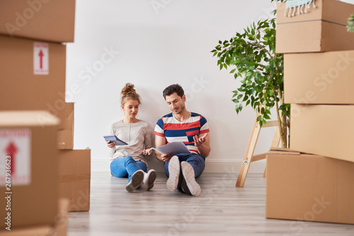 Worried couple examining expenses next to moving boxes photo