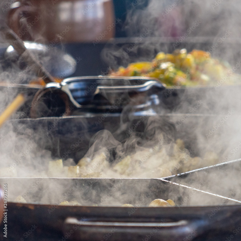 Shooting of large steaming pans, steam in the foreground focused, vegetable pan in the background deliberately blurred Shooting of large steaming pans, steam in the foreground focused, vegetable pan in the background deliberately blurred