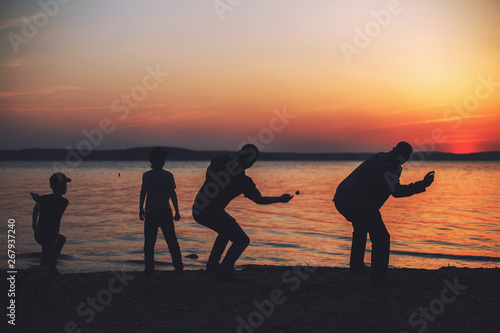 people at sunset throwing stones into the water