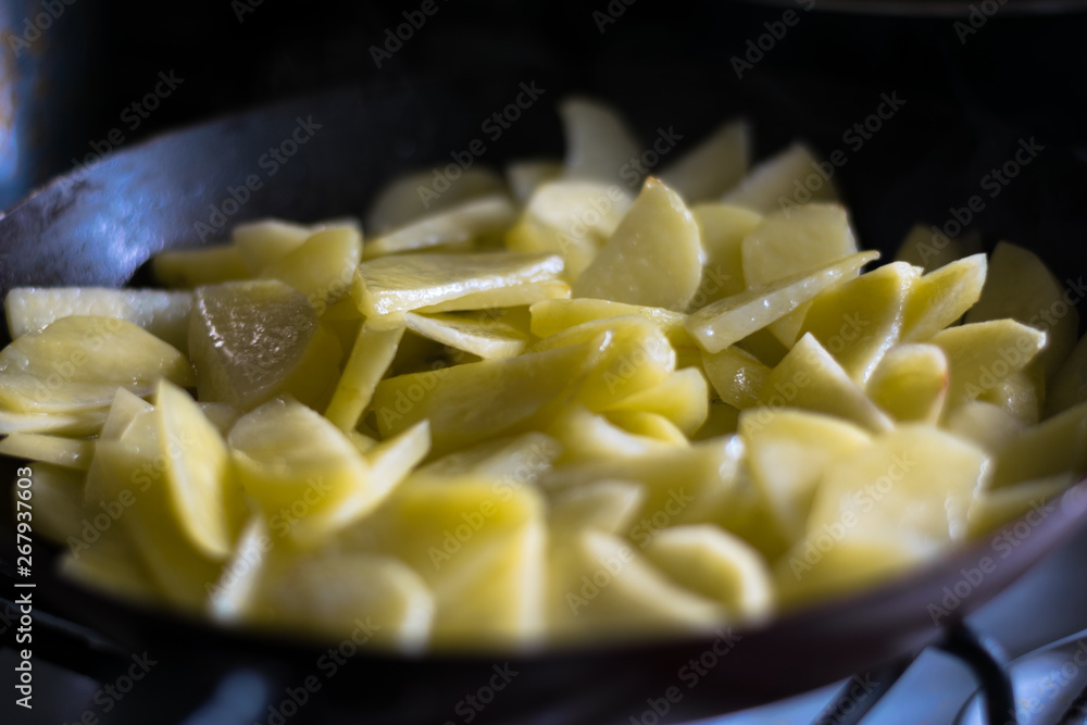 Raw potatoes are fried in a pan. The process of preparing fried potato Raw potatoes are fried in a pan. The process of preparing fried potato