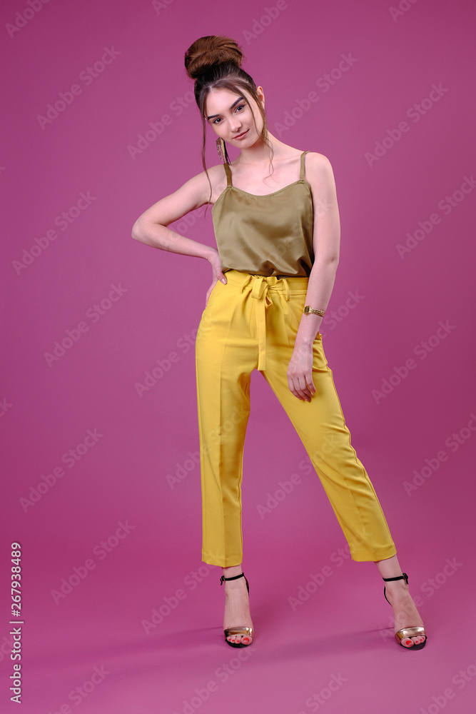Portrait of fashionable young woman dressed in yellow pants Portrait of fashionable young woman dressed in yellow pants