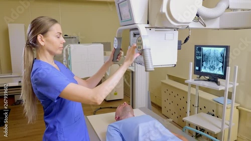Female Technician ajusts X-ray Machine, man lying