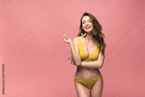 slim laughing girl in yellow swimsuit posing isolated on pink